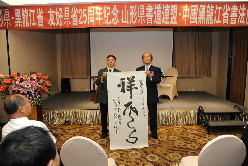 图1,胡志平秘书长向青柳祥云会长转赠张戈主席作品合影